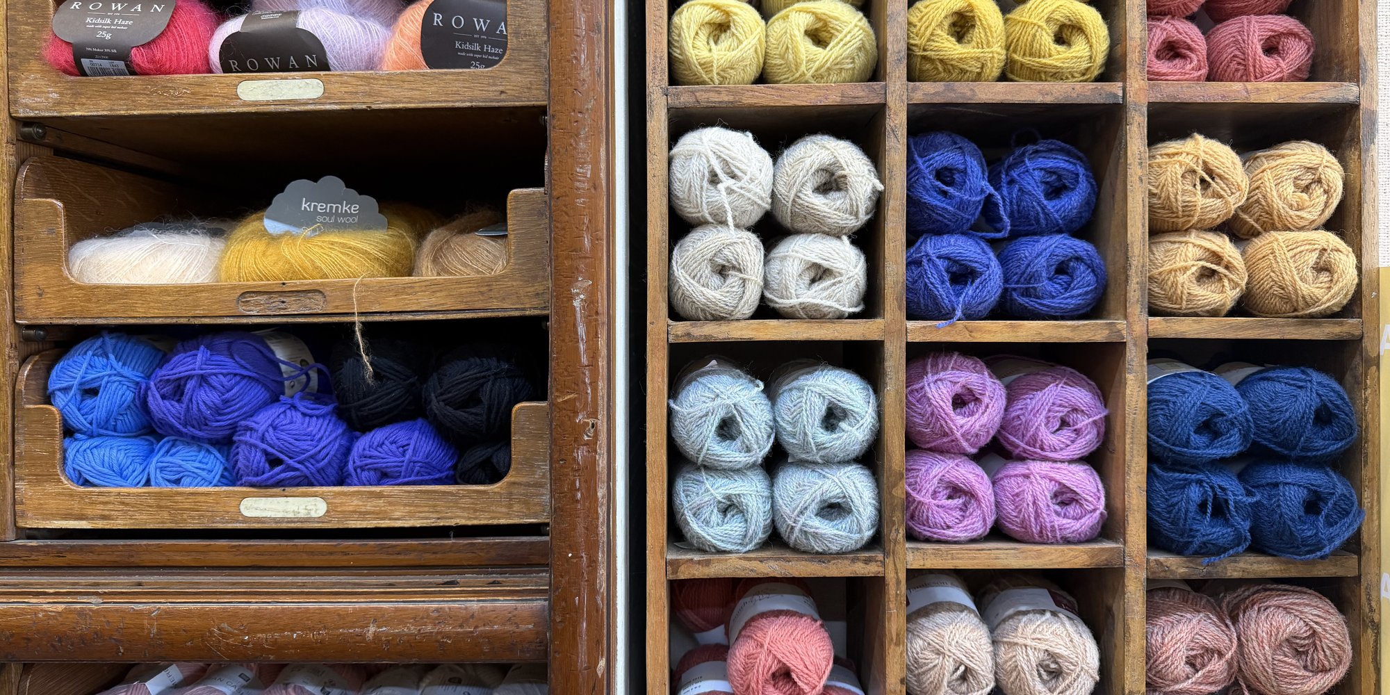 Wooden pigeonholes stacked with balls of yarn in every colour—a wall of threads to pull upon
